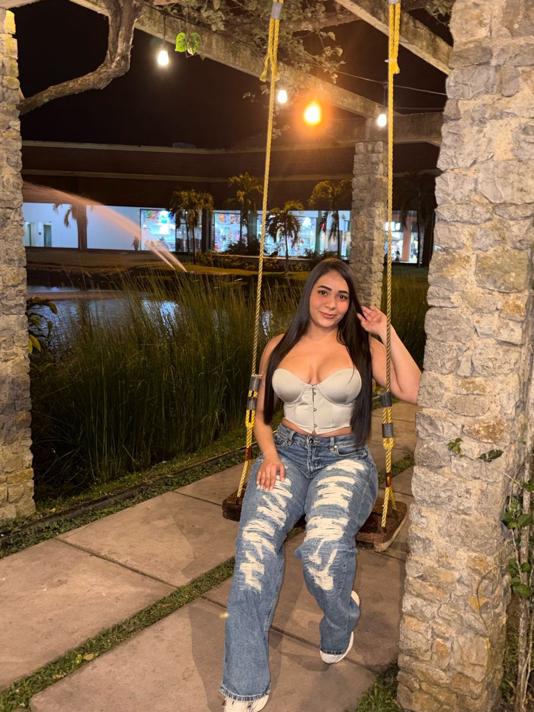 Woman in jeans sitting on a garden swing at night