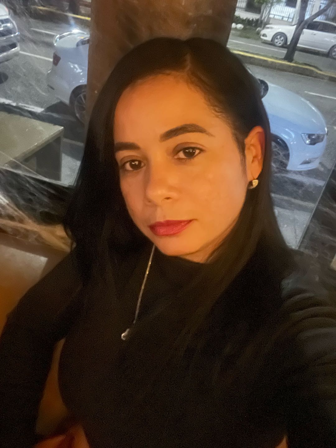 Woman with dark hair in a black top taking a selfie