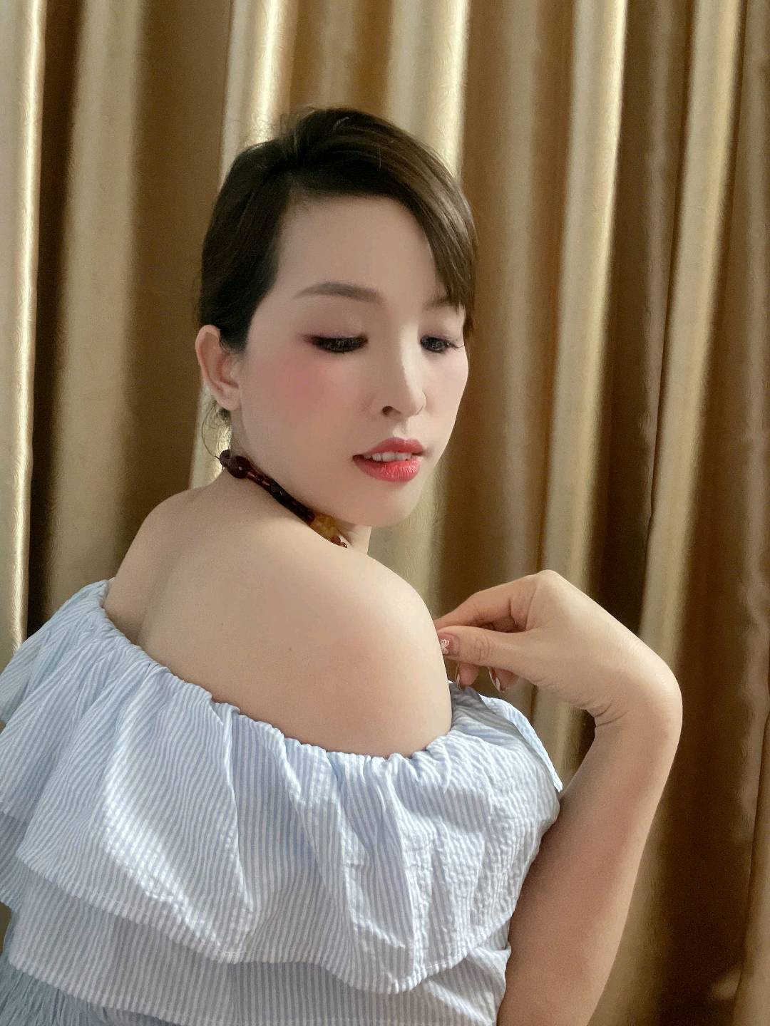 Woman with short dark hair in an off-shoulder striped top